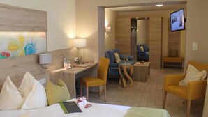 Une chambre d’hôtel équipée d’un lit, d’un bureau, d’une chaise, d’un canapé et d’un téléviseur fixé au mur.