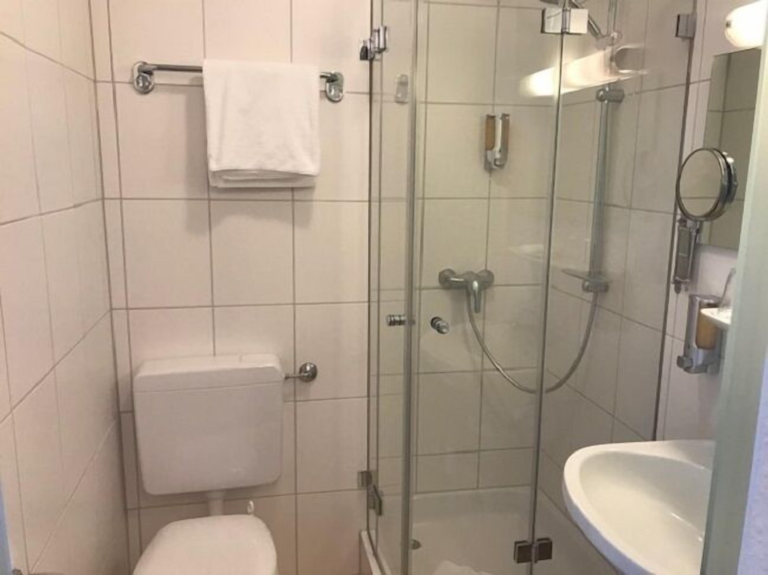 Un baño moderno con ducha de vidrio, inodoro y lavamanos.