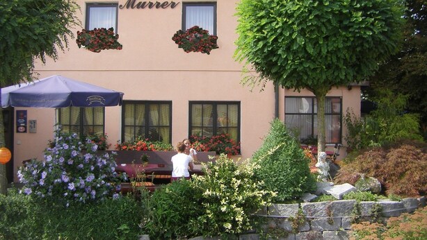 Un hôtel appelé « Hotel Landgasthof Murrer », doté d’une terrasse et de jardinières placées au-dessus des fenêtres.