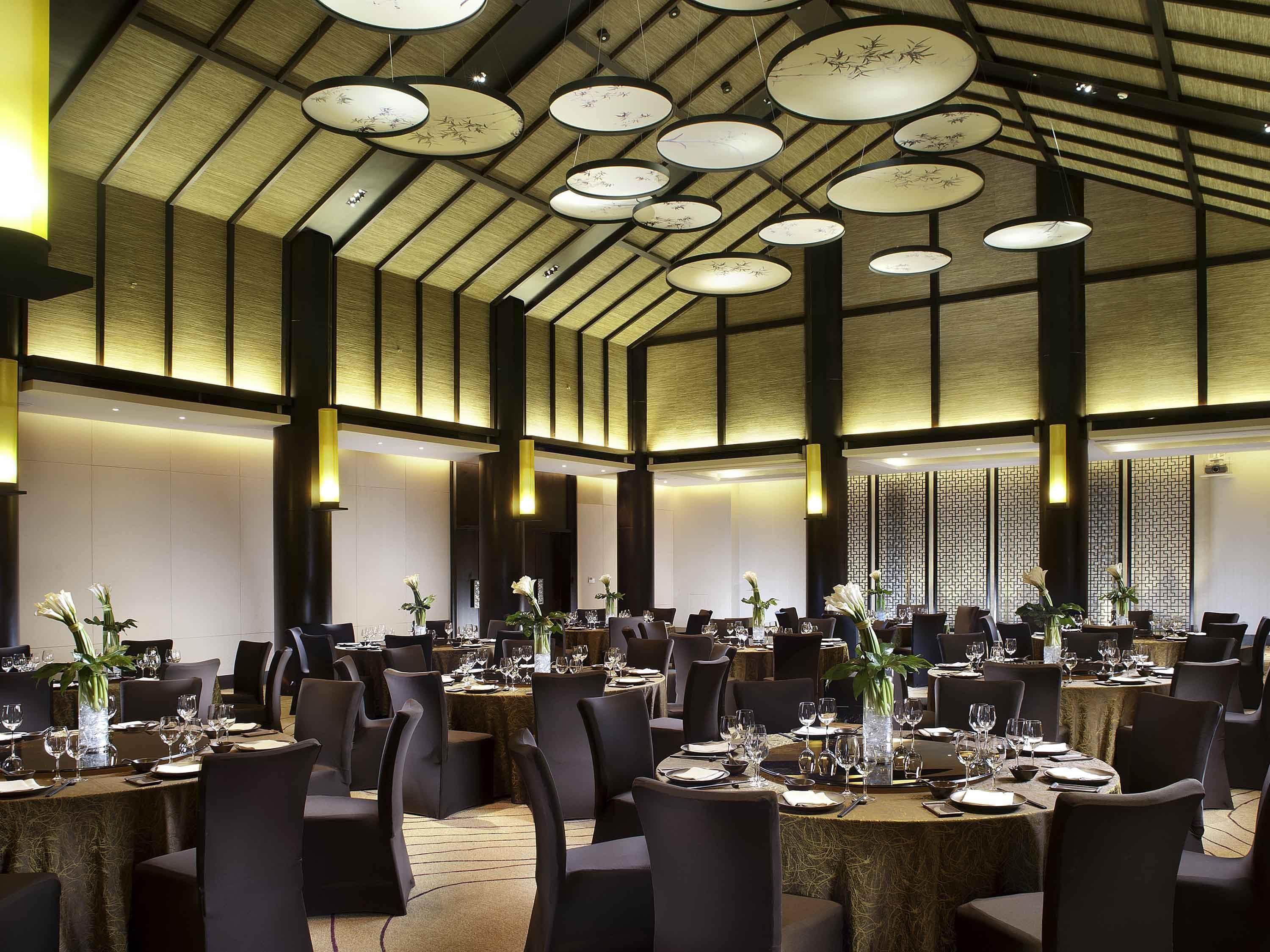 A spacious dining area with round tables, black chairs, and floral centerpieces.