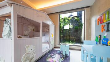 A children's playroom with a pink bunk bed, a bear-themed rug, and a LEGO wall.