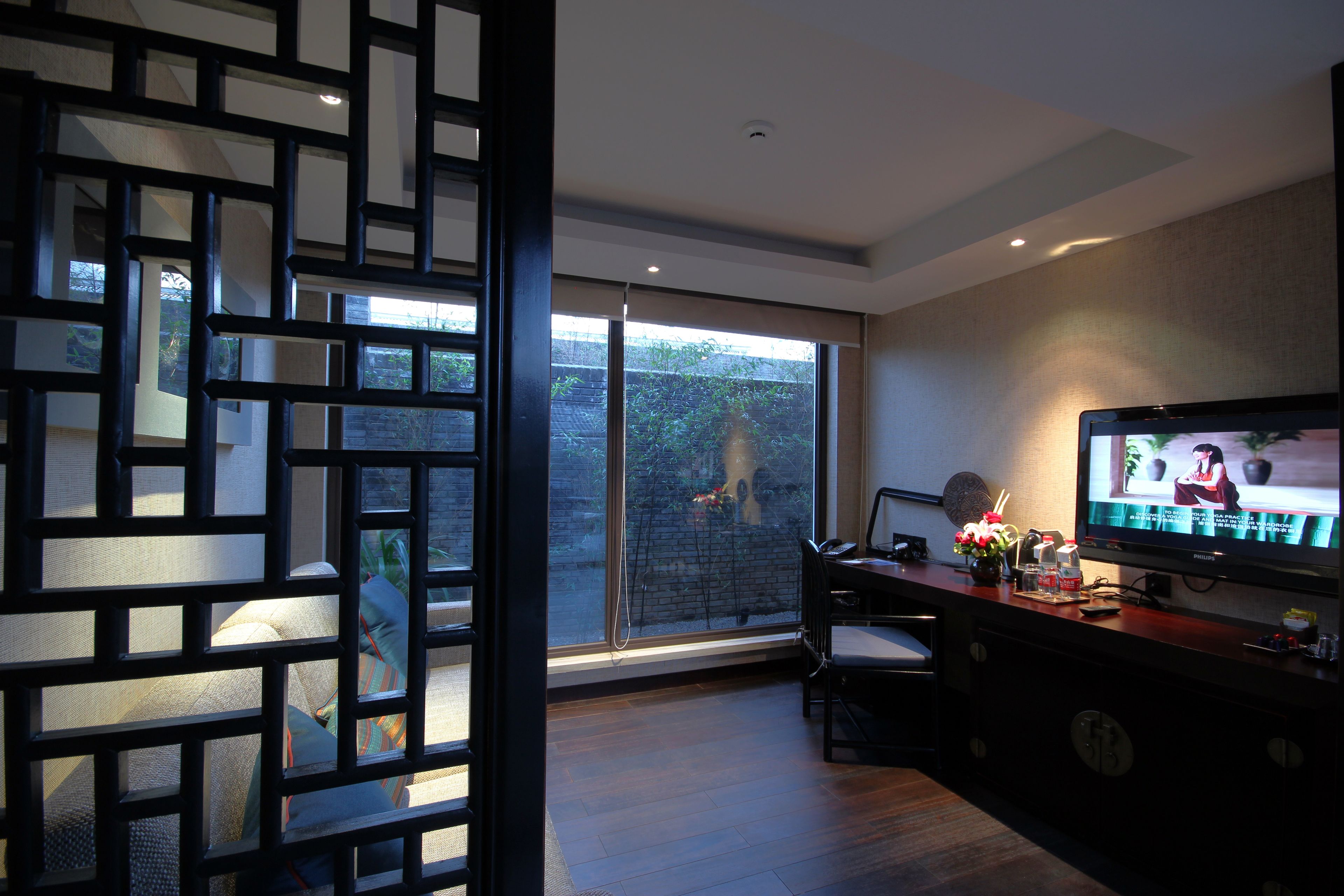 Una sala moderna con un televisor grande, un comedor y vistas a un jardín a través de un ventanal.