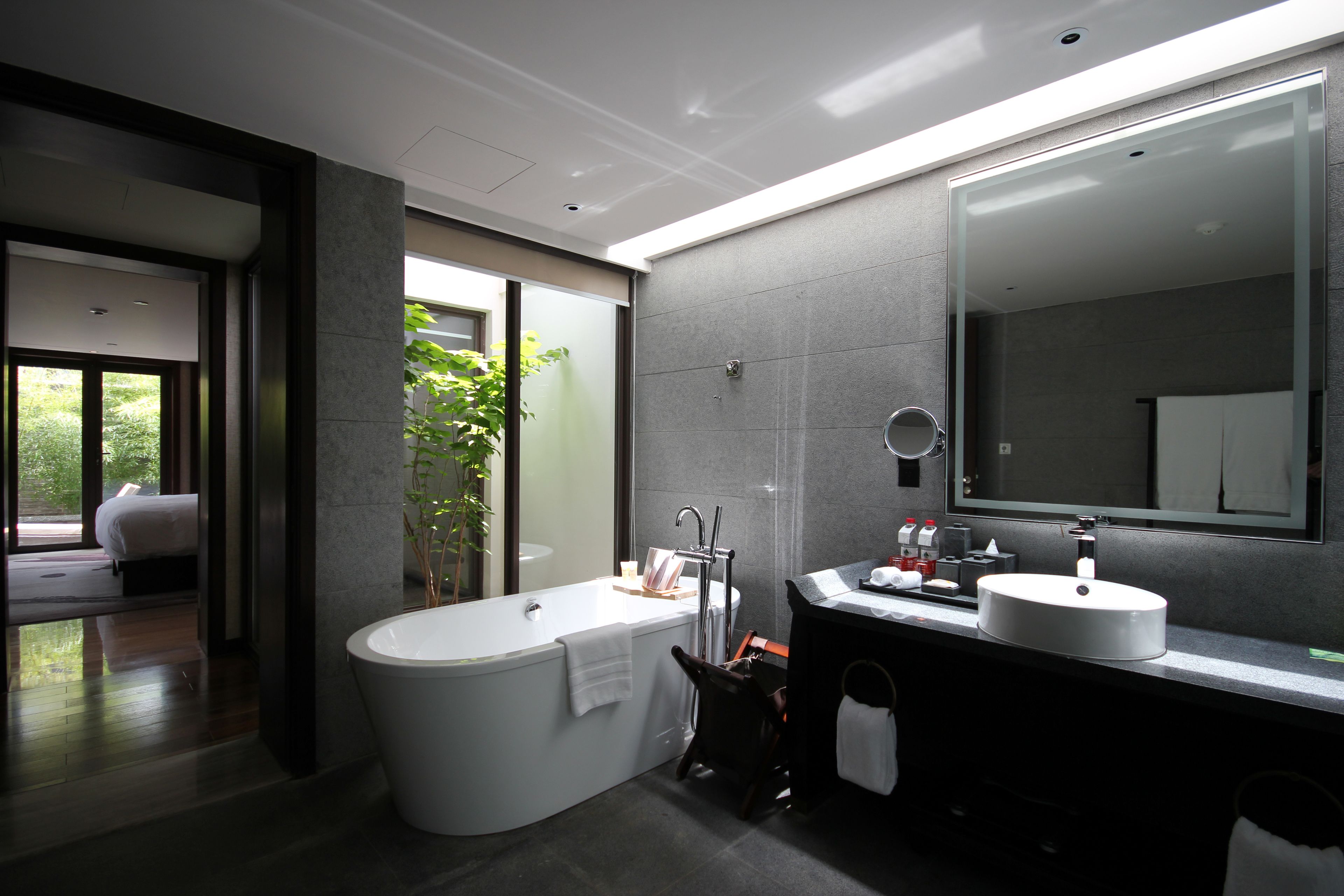 A modern bathroom with a freestanding bathtub, a double sink vanity, and a large mirror.