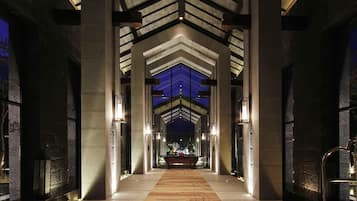 A hotel lobby with a central corridor, stone columns, and a patterned carpet.