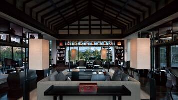 A modern interior with a high ceiling, large windows, and a cozy seating area.