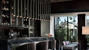 Un moderno bar con techo alto, barra con taburetes y zona de estar con sofá y sillones.