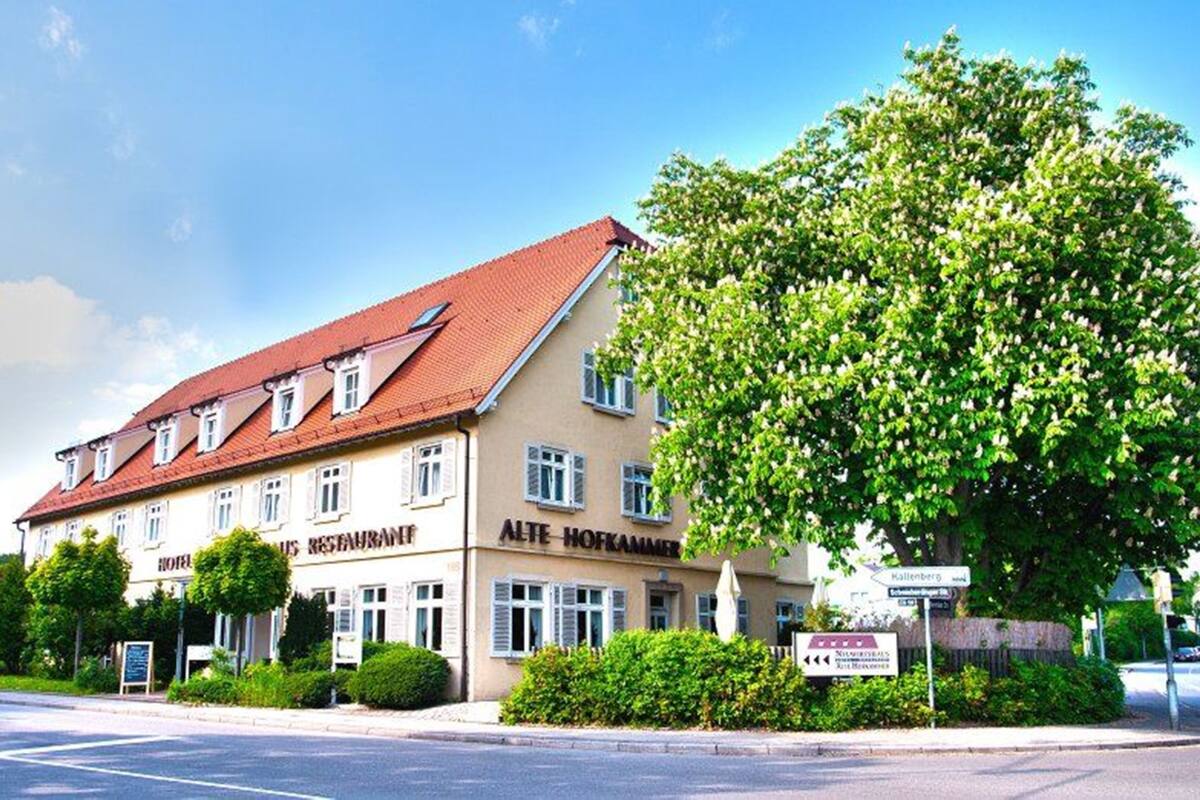 A two-story building with a red-tiled roof and a sign for 'Alte Hofkammer' restaurant.