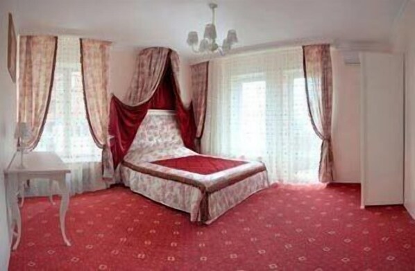 A bedroom with a bed, curtains, a chandelier, and a red carpet. - Royal City Hotel (Kyiv)