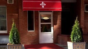 The exterior of the Royal City Hotel with a red awning, a white door, and steps leading up to the entrance. - Royal City Hotel (Kyiv)