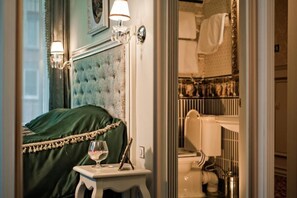 A bedroom with a green upholstered headboard, a bedside table with a glass of water, and a framed picture above the bed. - Royal City Hotel (Kyiv)