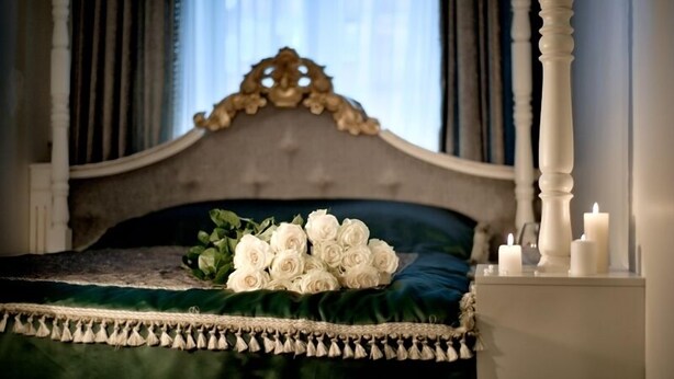 A bed with a green velvet bedspread and a decorative headboard. - Royal City Hotel (Kyiv)