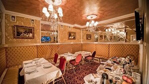 A dining area with tables set for a meal, a patterned carpet, and a chandelier. - Royal City Hotel (Kyiv)
