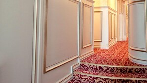A hallway with ornate white paneling and a red patterned carpet. - Royal City Hotel (Kyiv)