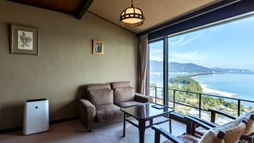 A room with a sofa, a small table, a white appliance, and a view of the ocean.