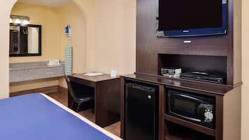 A hotel room with a bed, a desk, a TV, a microwave, and a mini-fridge.