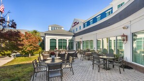 A patio area with outdoor seating and a view of the garden inn building. - Hilton Garden Inn Columbia Northeast (Columbia)