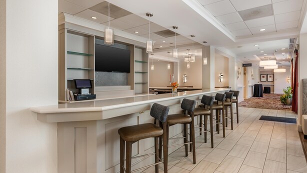 A modern hotel bar with a long counter, bar stools, and pendant lighting. - Hilton Garden Inn Columbia Northeast (Columbia)