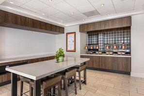 A modern kitchen with a central island, bar stools, and a dining table. - Hilton Garden Inn Columbia Northeast (Columbia)