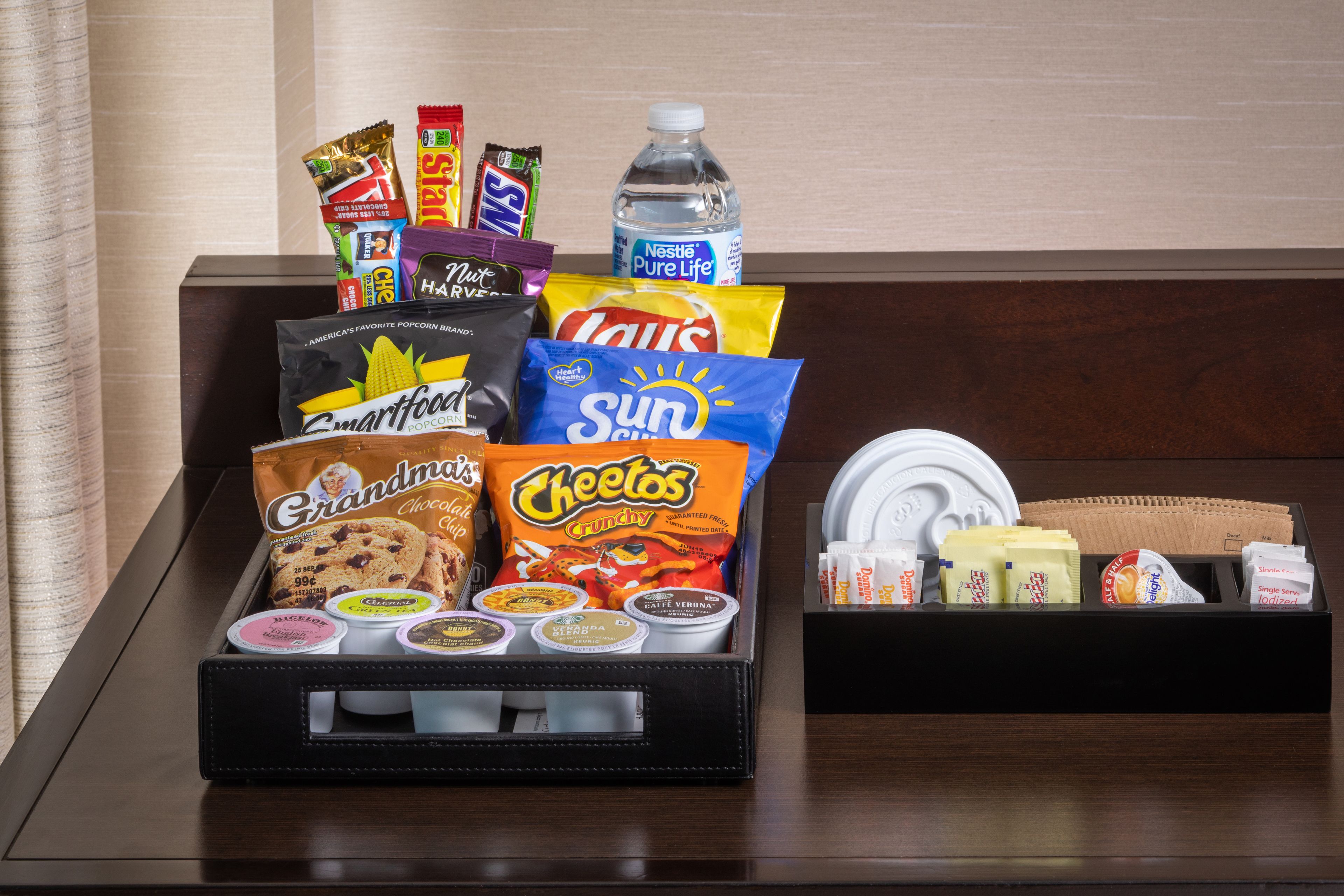 A tray with snacks and condiments, including Smartfood, Cheetos, and various other items.