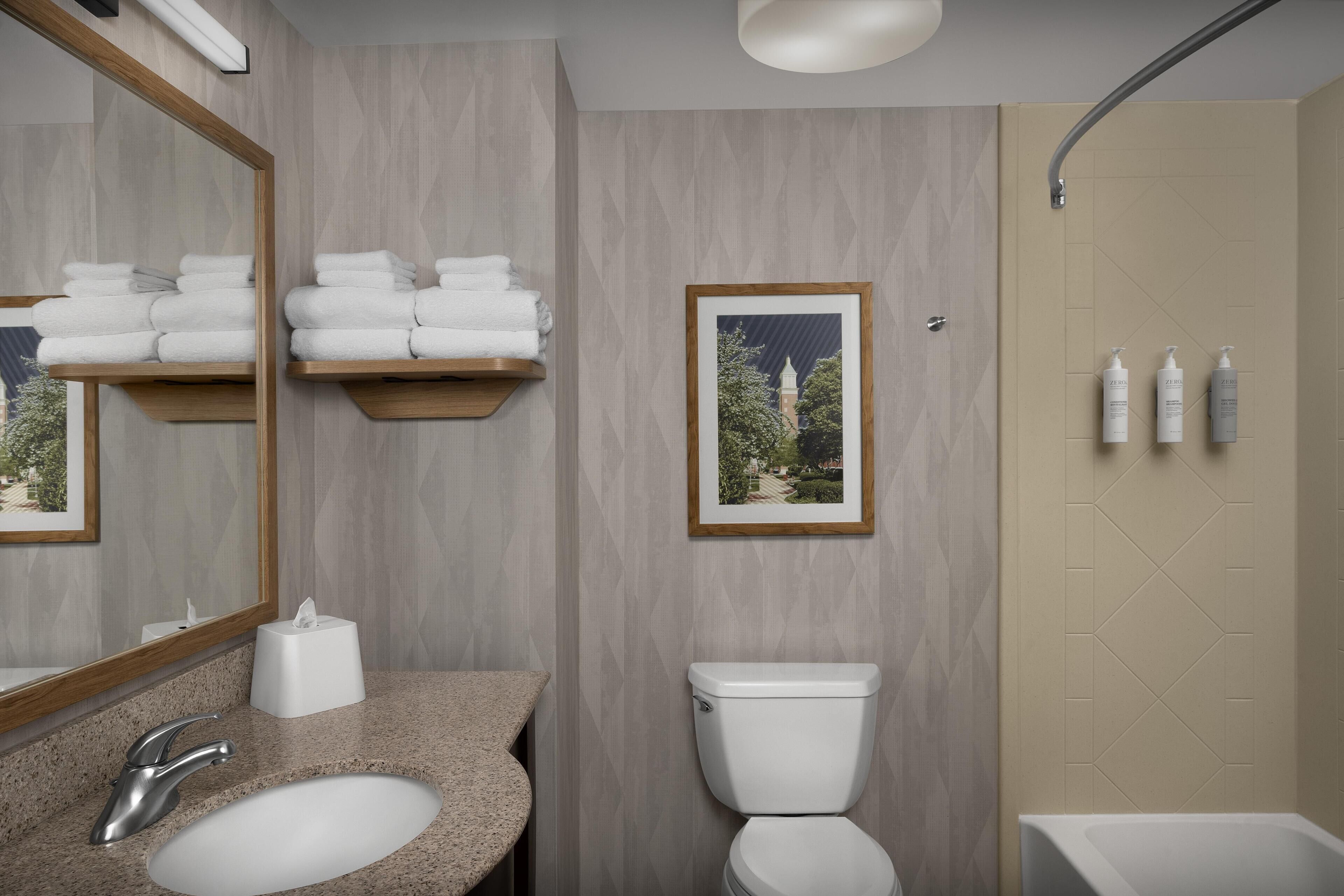 A modern bathroom with a granite sink, a toilet, and a shower.