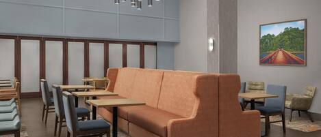 A modern dining area with a sofa, tables, chairs, and a painting on the wall.
