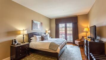 A hotel room with a bed, a desk, a TV, and a window with curtains.