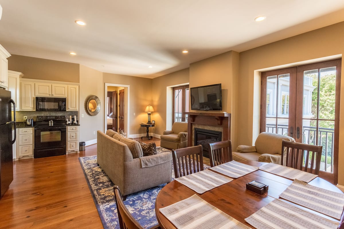 A spacious living room with a fireplace, a dining area with a wooden table, and a kitchen with modern appliances.