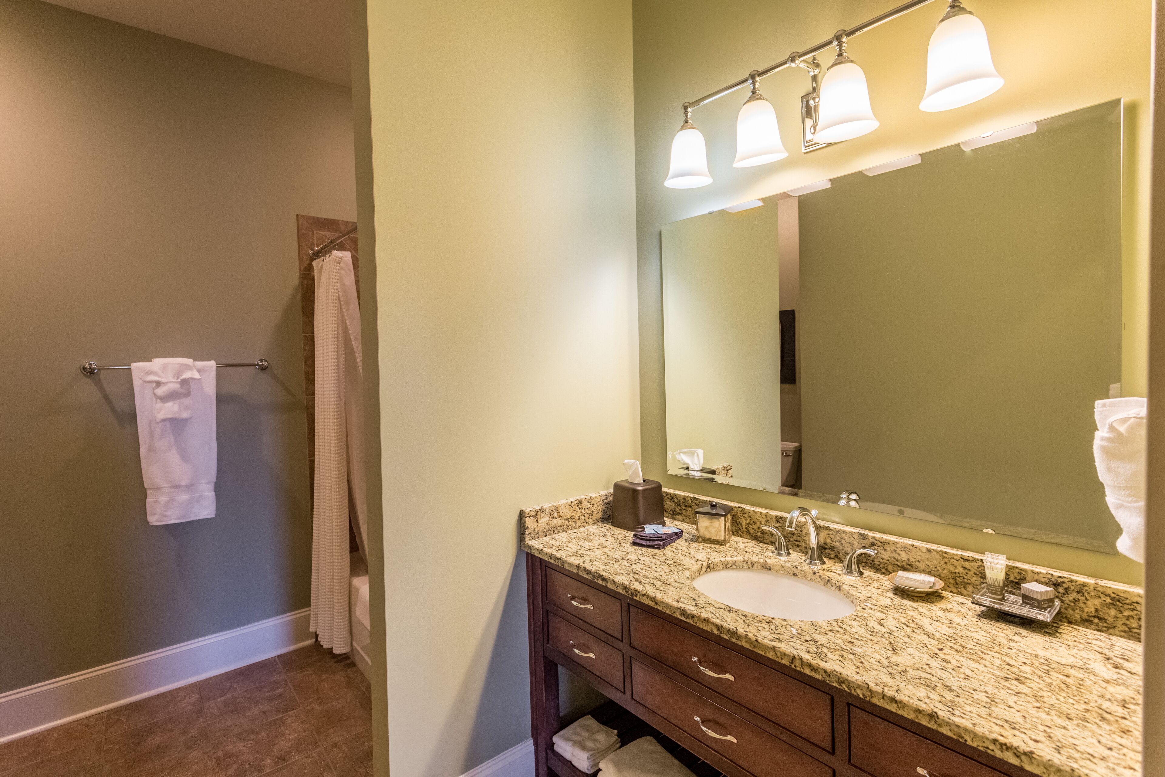 A bathroom with a granite countertop sink, a large mirror, and a towel rack.