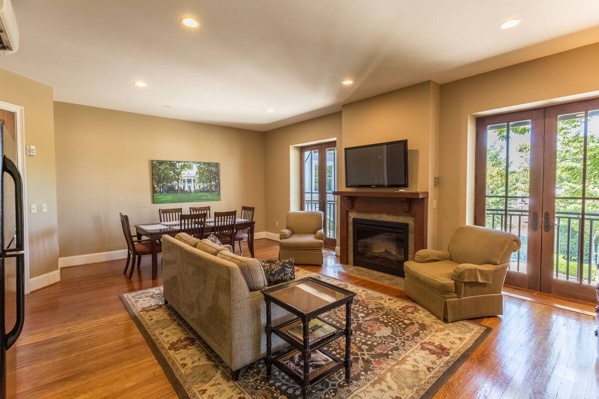 A spacious living room with a sofa, armchair, and a fireplace.