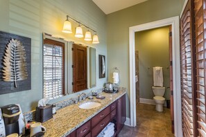 A bathroom with a granite countertop, a sink, a mirror, and a toilet.