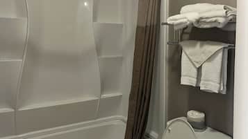 A bathroom with a bathtub, a toilet, and a towel rack with folded towels.