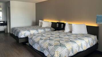 A modern hotel room with two beds, a dark headboard, and a small bedside table.