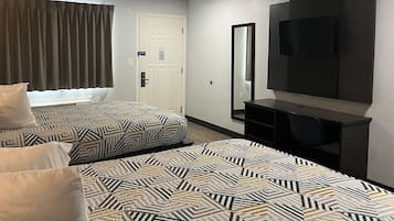 Une chambre d’hôtel avec deux lits, une télévision, un miroir et une porte.