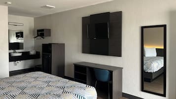 Una habitación de hotel moderna con una cama, un escritorio, una silla, un espejo y un armario.
