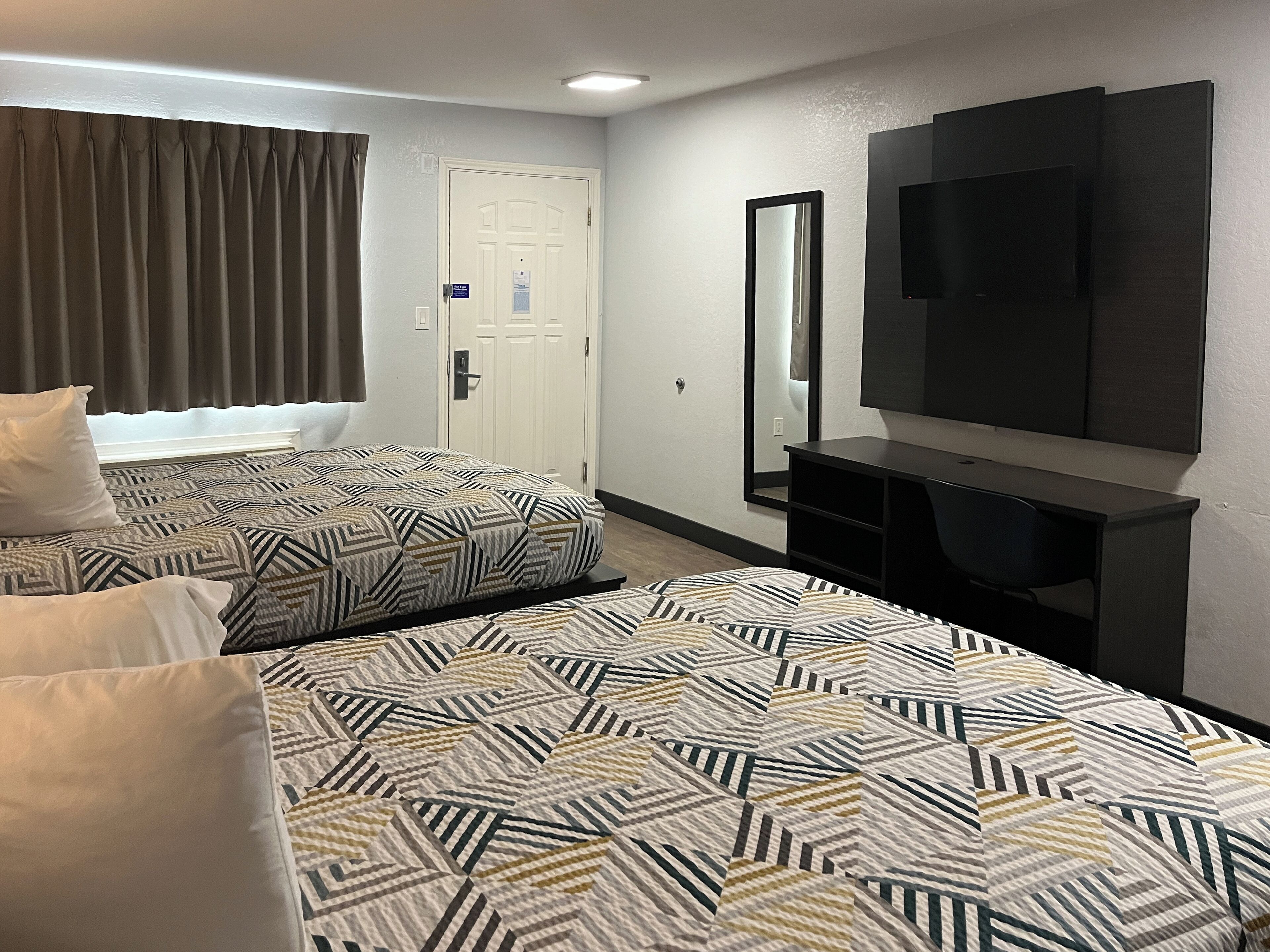 Habitación de hotel con dos camas, una televisión, un espejo y una puerta.