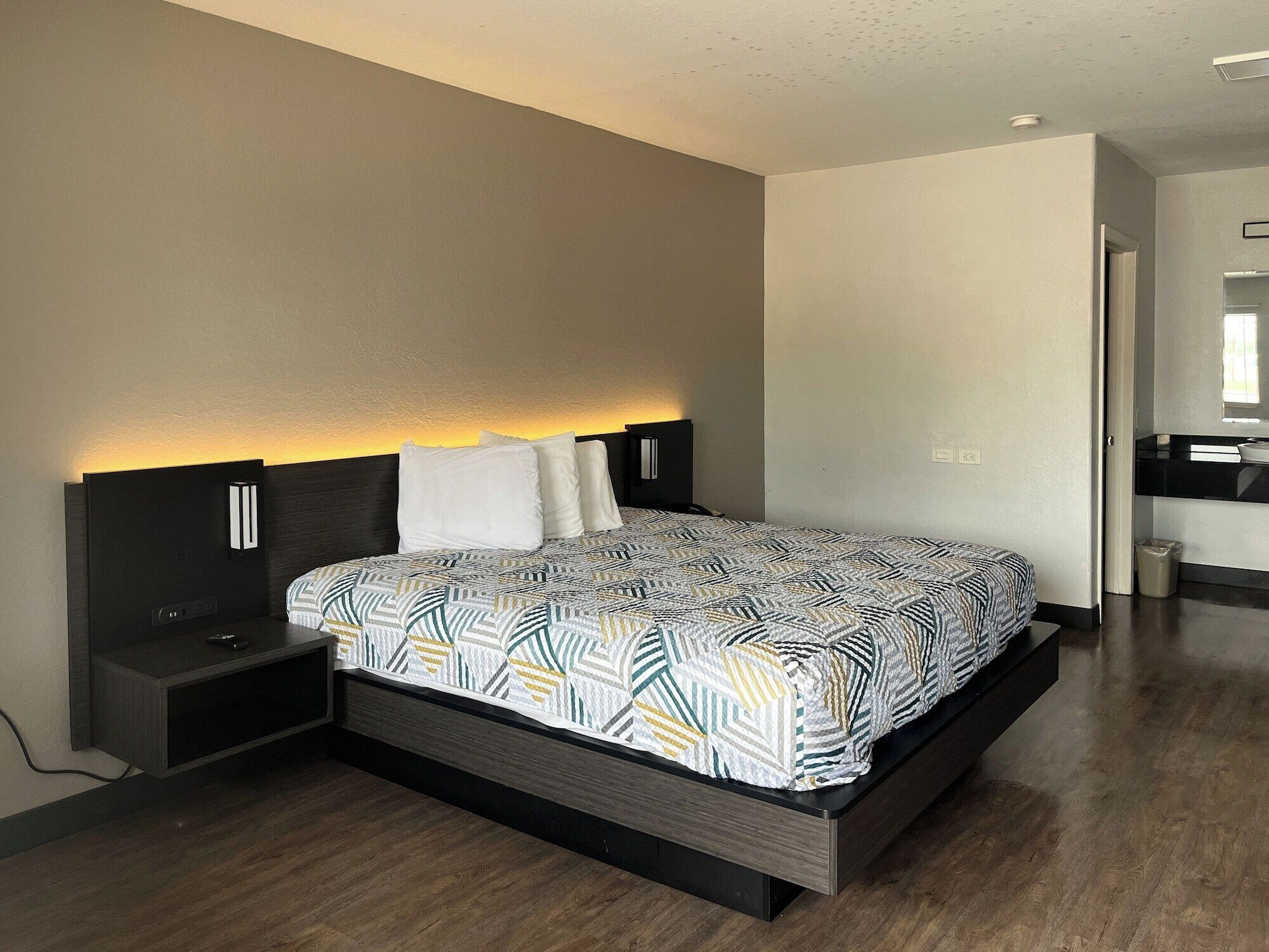 Un dormitorio moderno con cama, mesitas de noche y un banco empotrado.
