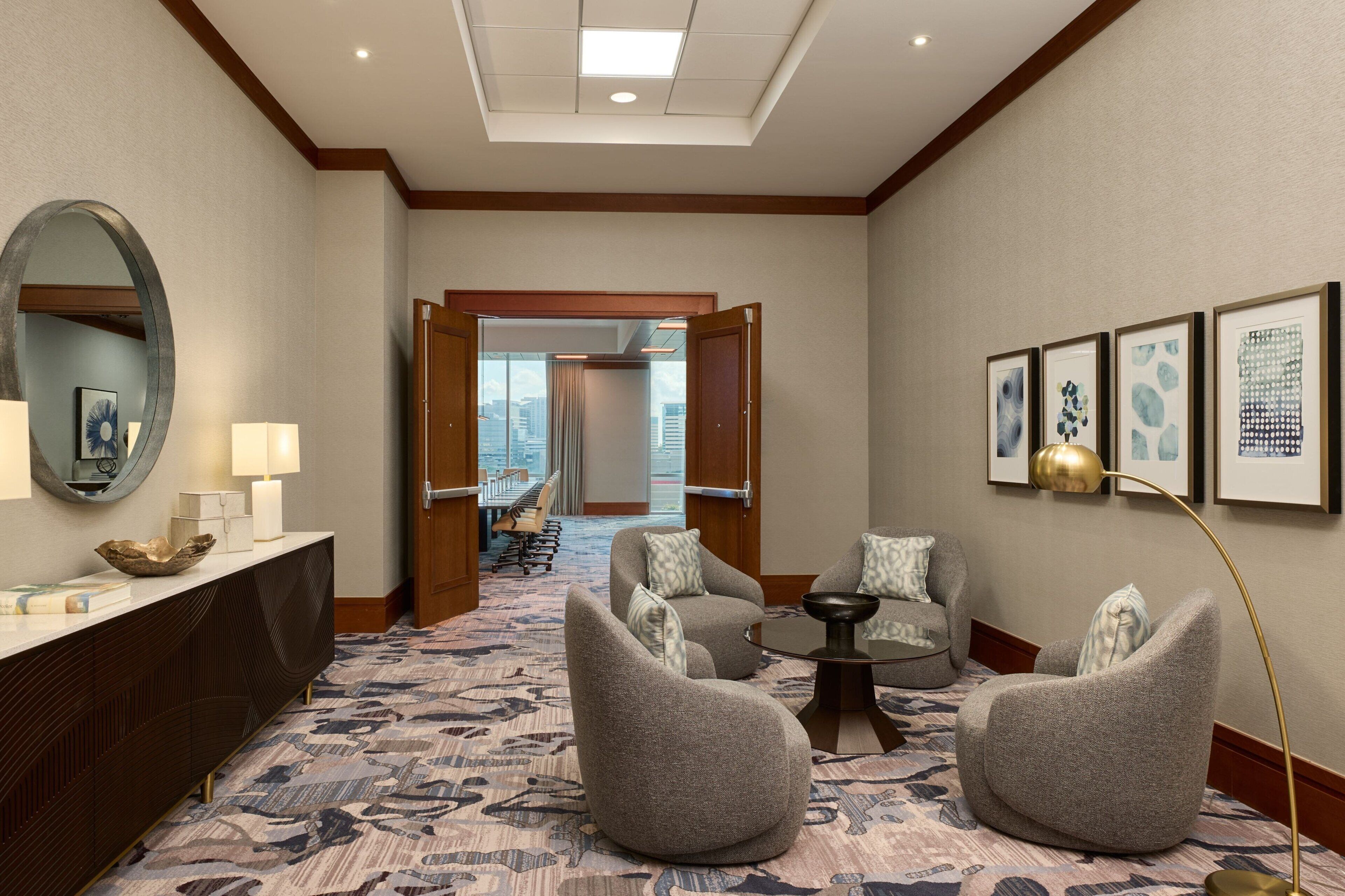 Un vestíbulo de hotel con una recepción, dos sillones, una mesa de centro y un espejo grande.