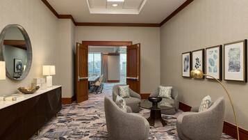 Un vestíbulo de hotel con una recepción, dos sillones, una mesa de centro y un espejo grande.