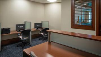 A conference room with three desks, each with a computer monitor, keyboard, and office chair.