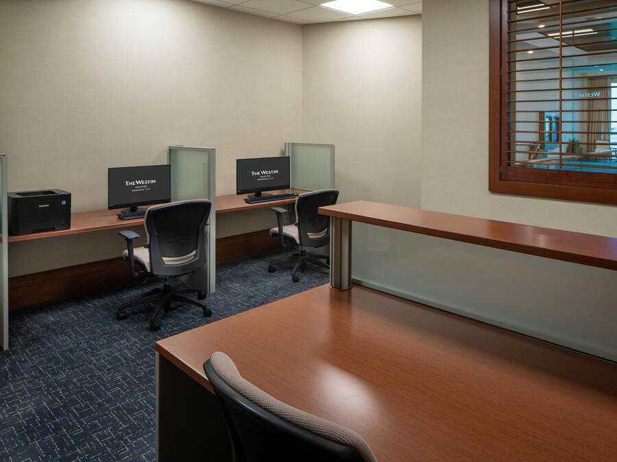 A conference room with three desks, each with a computer monitor, keyboard, and office chair.