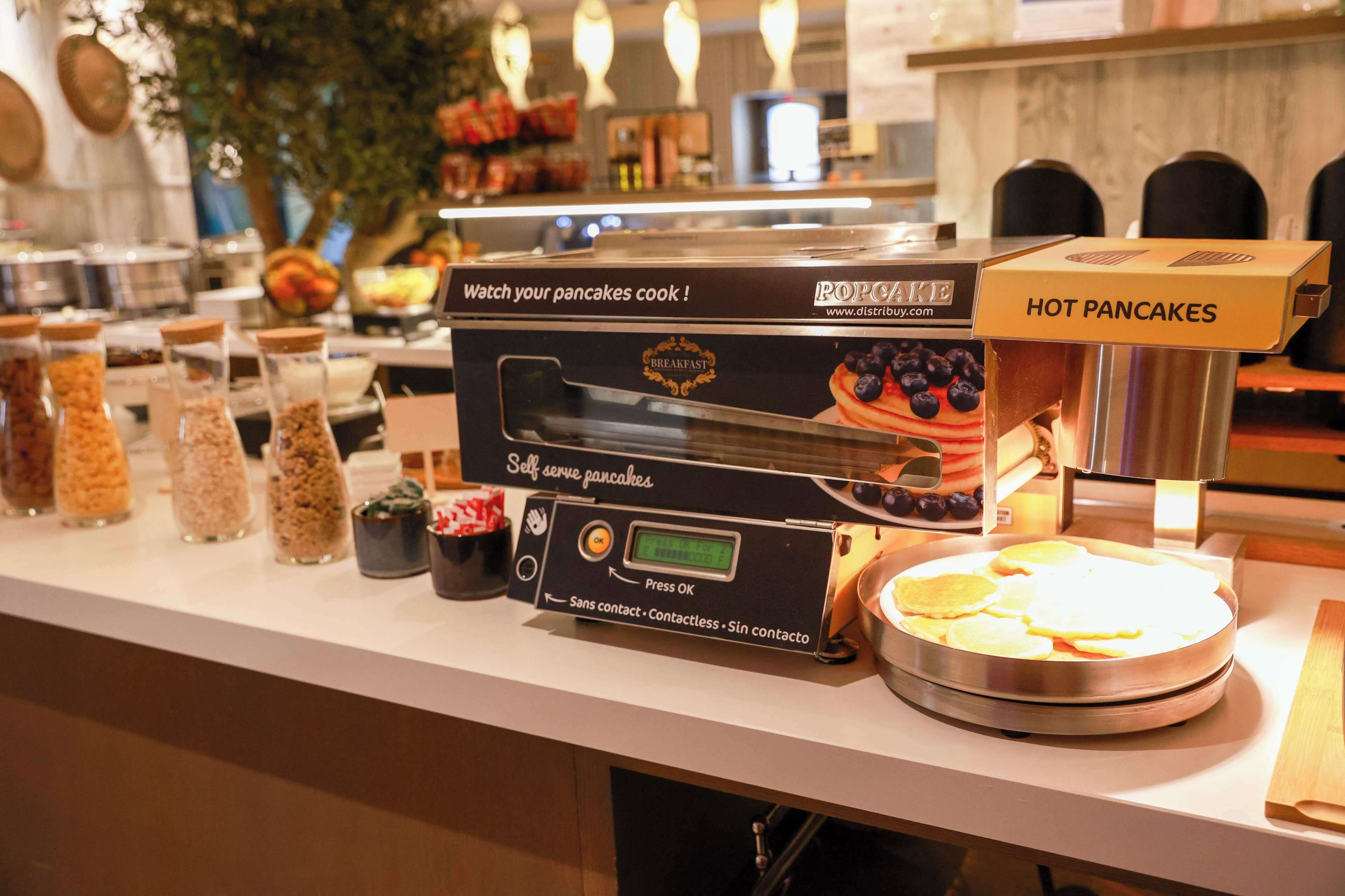 A self-serve pancake station with a digital display and a box labeled "HOT PANCAKES".