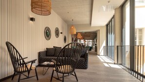 Un hall d’entrée spacieux, aménagé avec un mobilier moderne, comprenant un canapé et deux fauteuils, ainsi que des œuvres d’art décoratives accrochées aux murs.