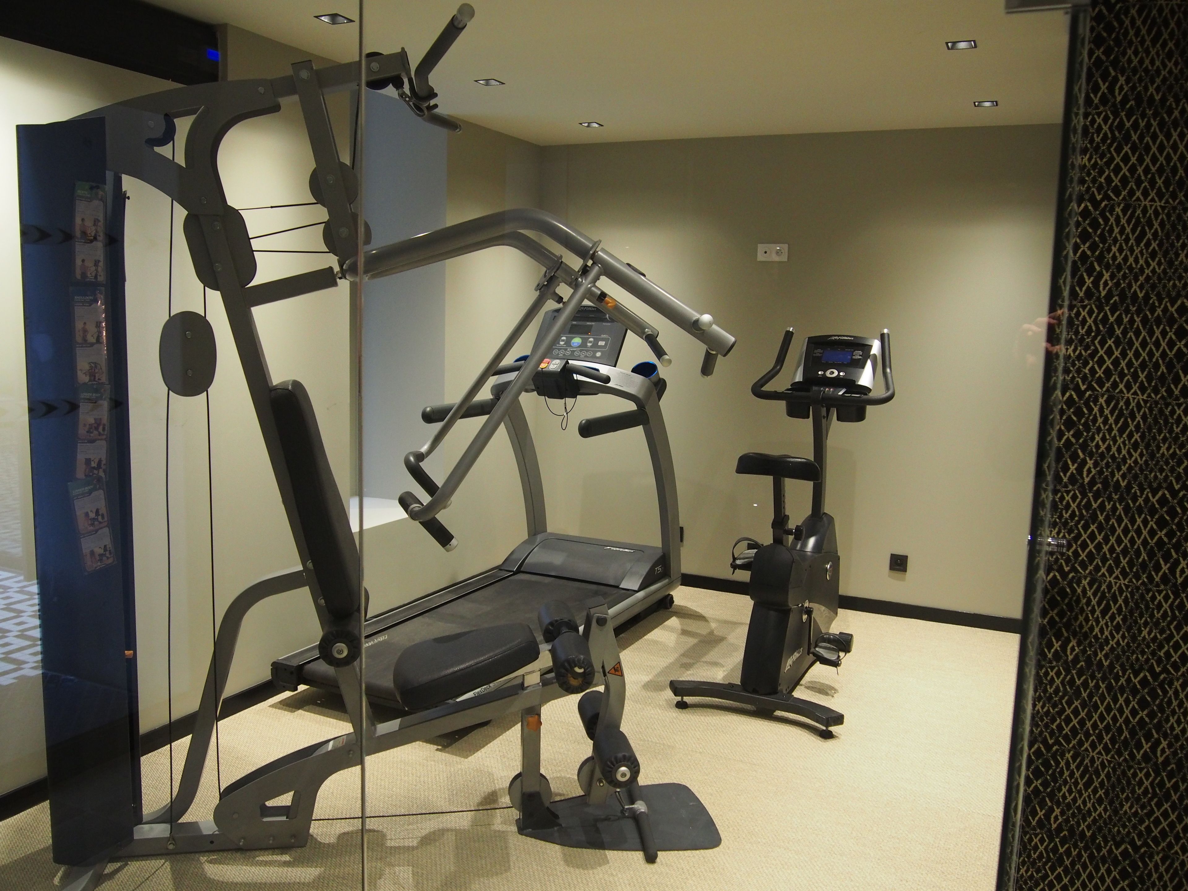A gym with cardio machines, weight machines, and a bench.