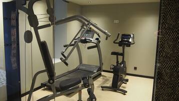 A gym with cardio machines, weight machines, and a bench.