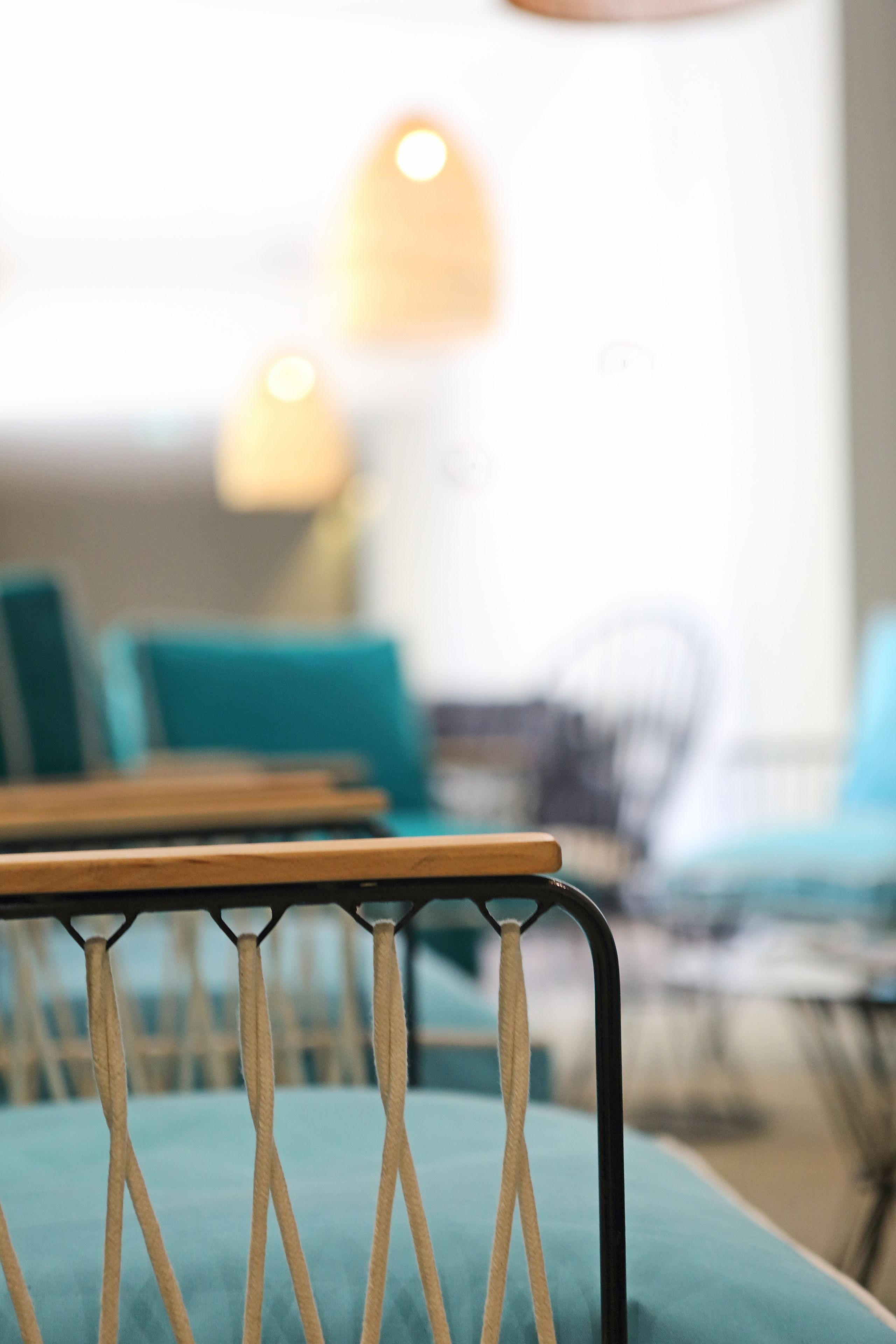 A close-up of a chair with a wooden frame and a teal cushion.