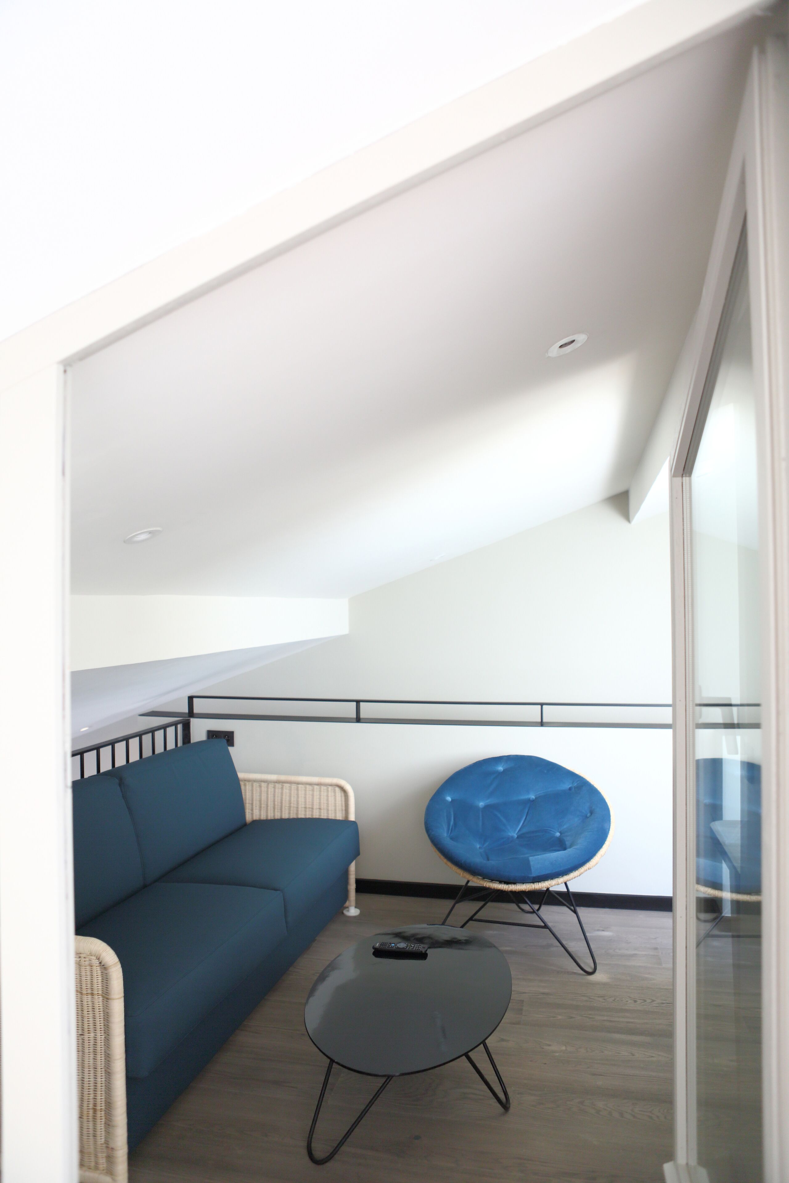 A modern living room with a blue sofa, a round black table, and a blue chair.