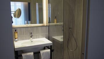 Een moderne badkamer met een grote spiegel, een witte wastafel en een douchehoek.