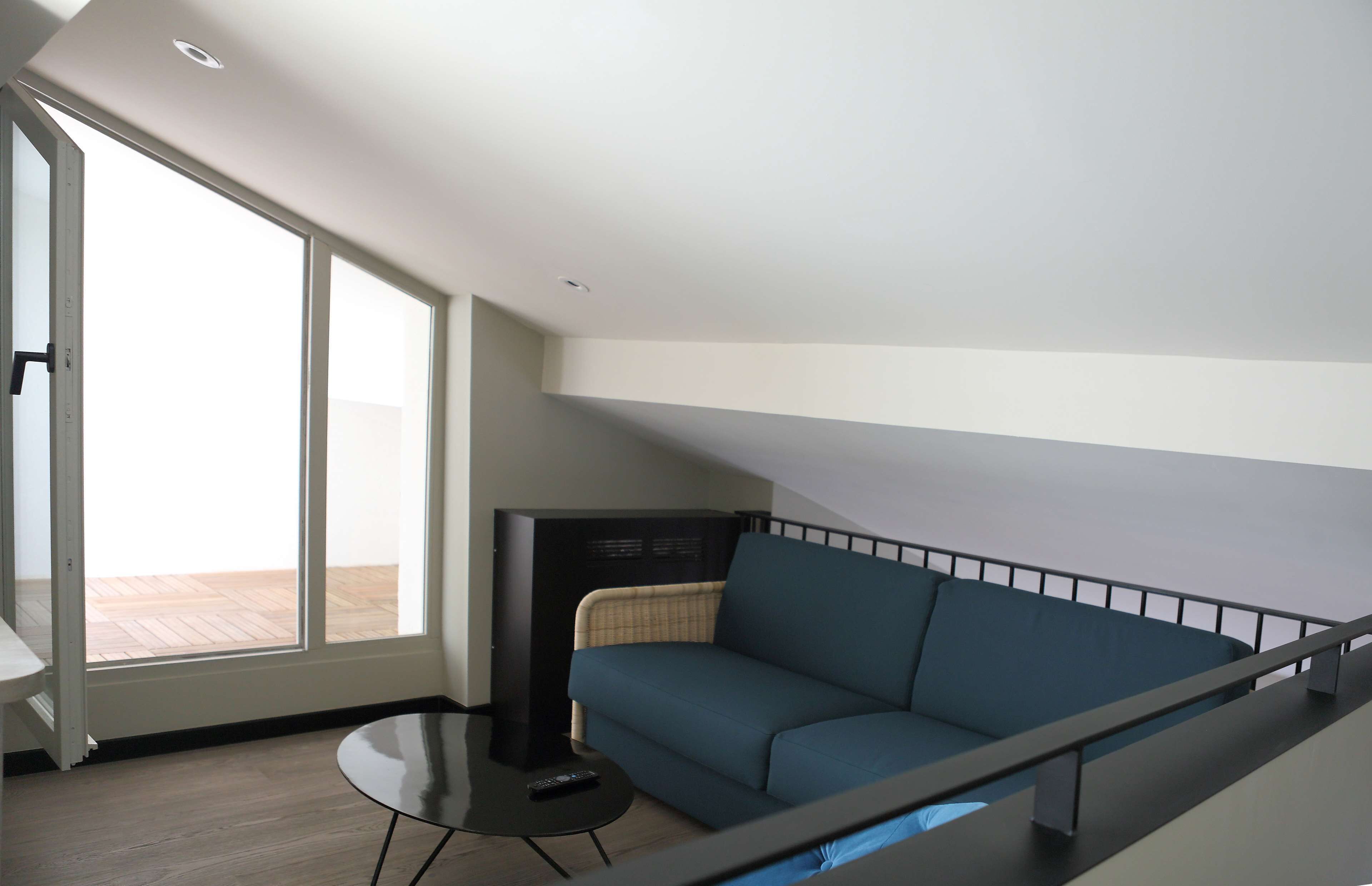 A modern living room with a sofa, a small table, and a television.