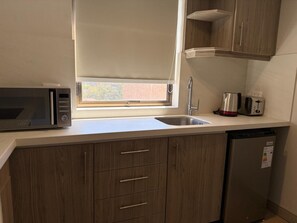 Cocina compacta con microondas, tostadora y lavabo.