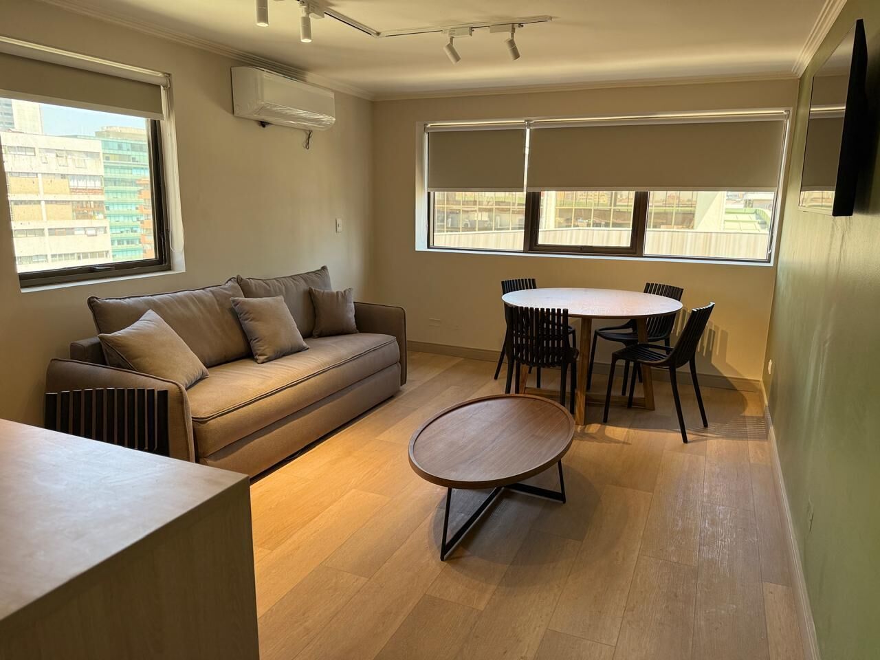 Una sala de estar moderna con un sofá, una mesa redonda para café y una mesa de comedor con sillas.